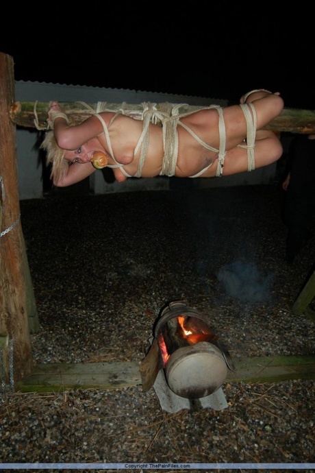 Naked blonde with an apple in her mouth is roasted over a fire while rope tied 37734725